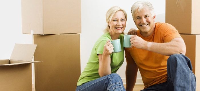 Senior couple sitting with boxes holding coffee mugs